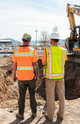 men in safety vests standing in front of a construction vehicle